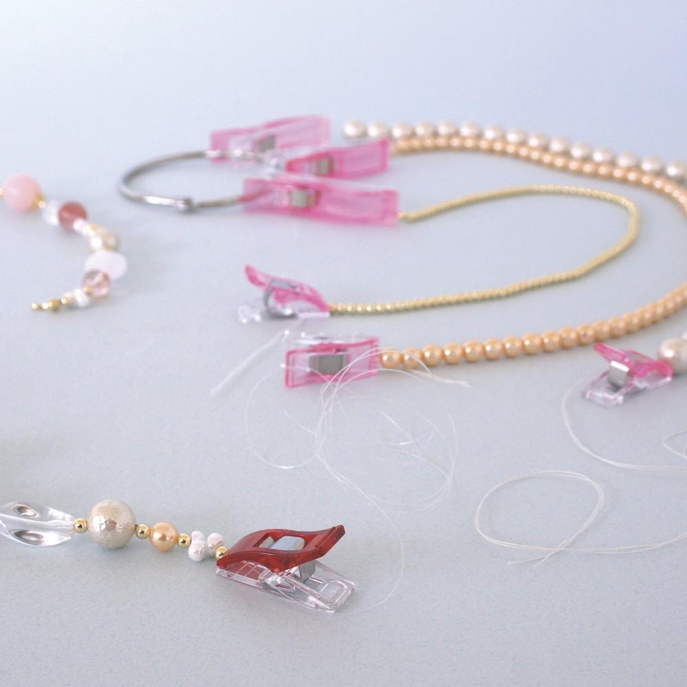 a collection of colorful jewelry, including necklaces, beads, and clasps, arranged on a light-colored surface.
