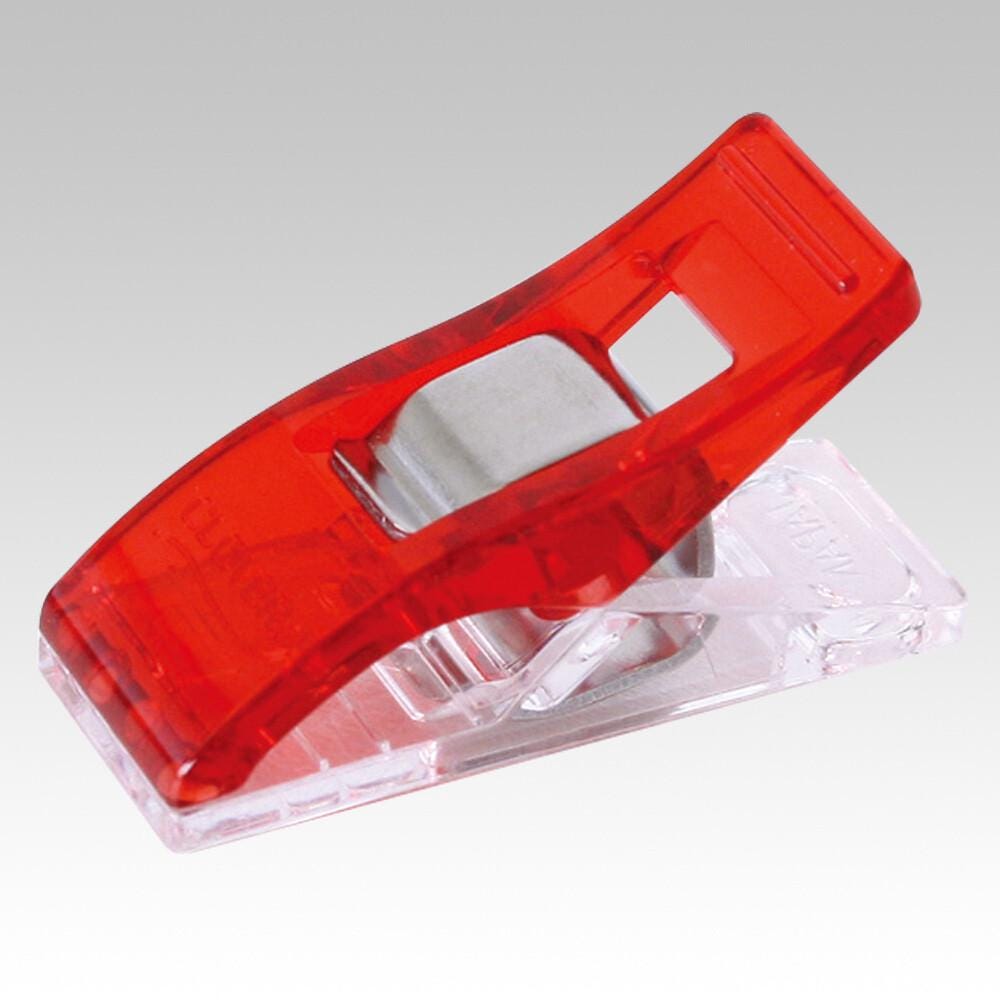 A red plastic clip with a silver metal piece attached to it, sitting on a clear plastic stand.
