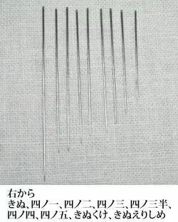a collection of metal needles arranged in a row on a textured surface.