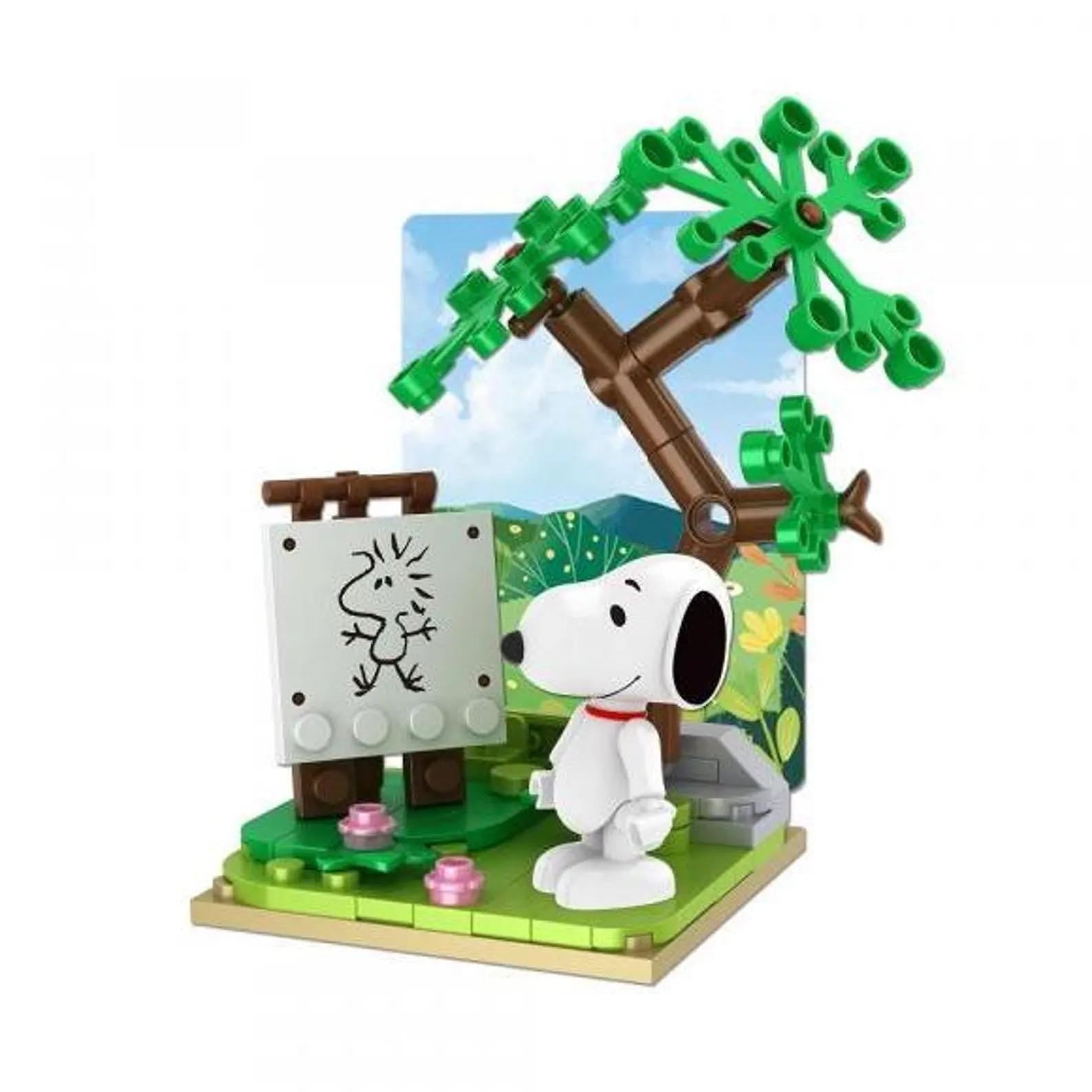 A Peanuts-themed Lego set featuring a Snoopy figurine standing next to a tree with a drawing of Snoopy on a canvas.