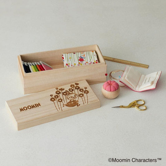 a wooden box with a floral design, a pair of gold scissors, and a small wooden ball with a pink exterior.