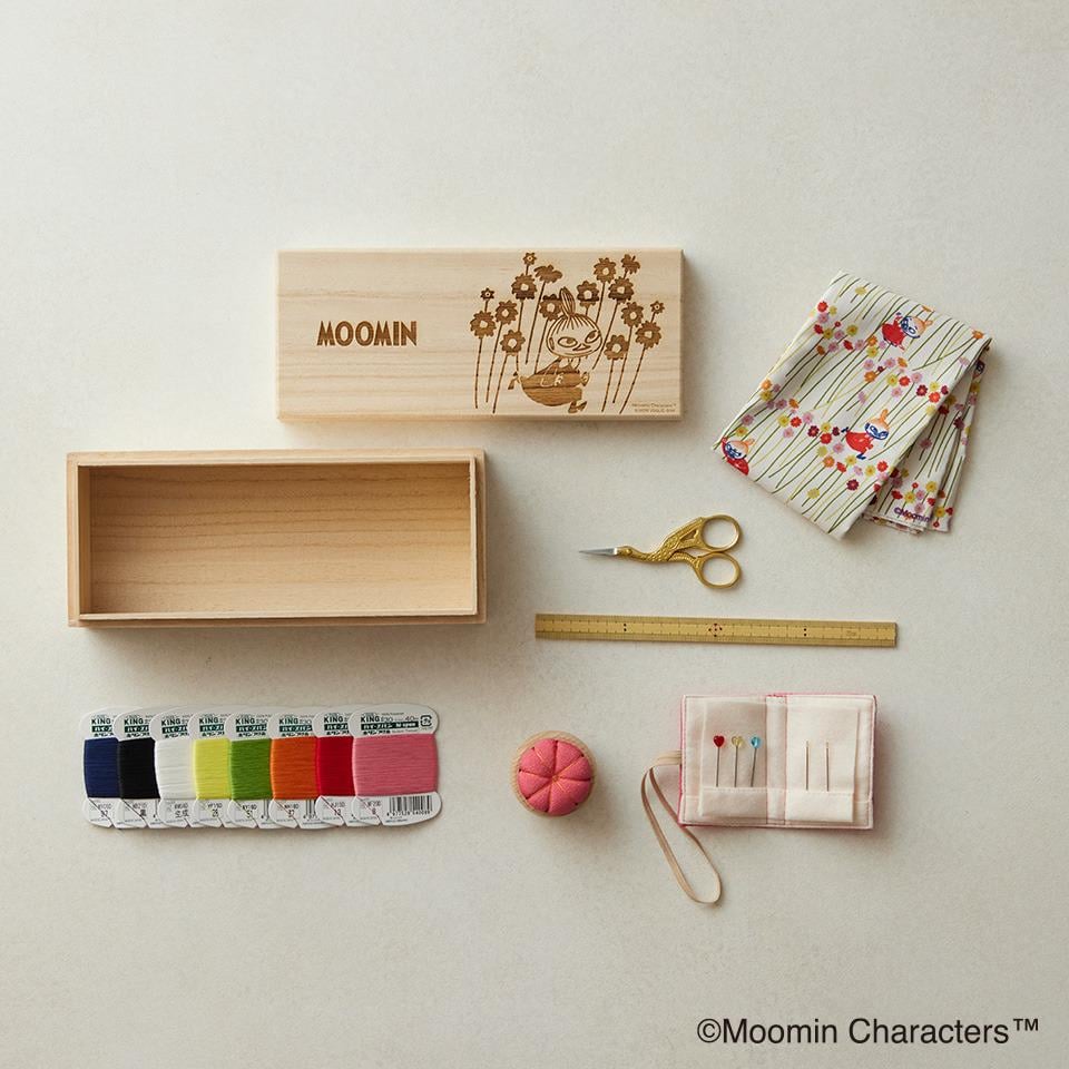 various craft supplies, including a wooden box, scissors, a ruler, a sewing kit, and a collection of colorful spools of thread.