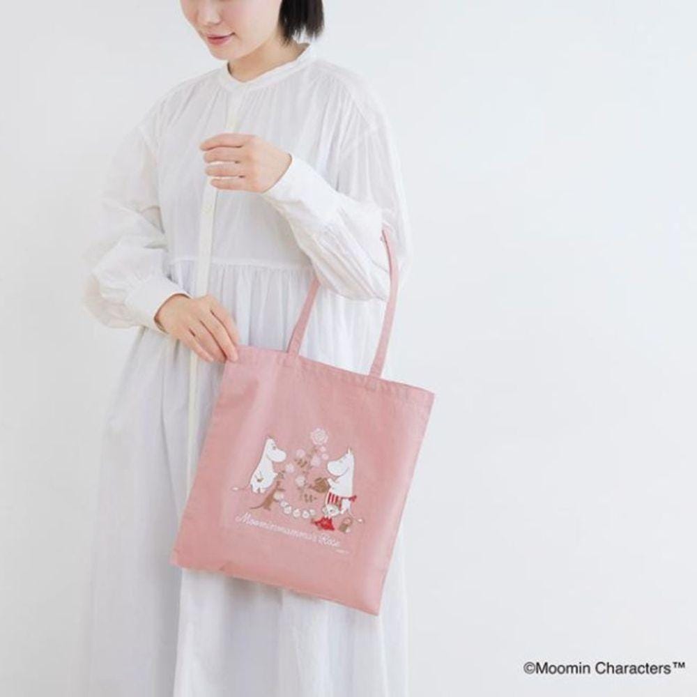 A woman in a white dress is holding a pink tote bag with a design featuring two white polar bears.