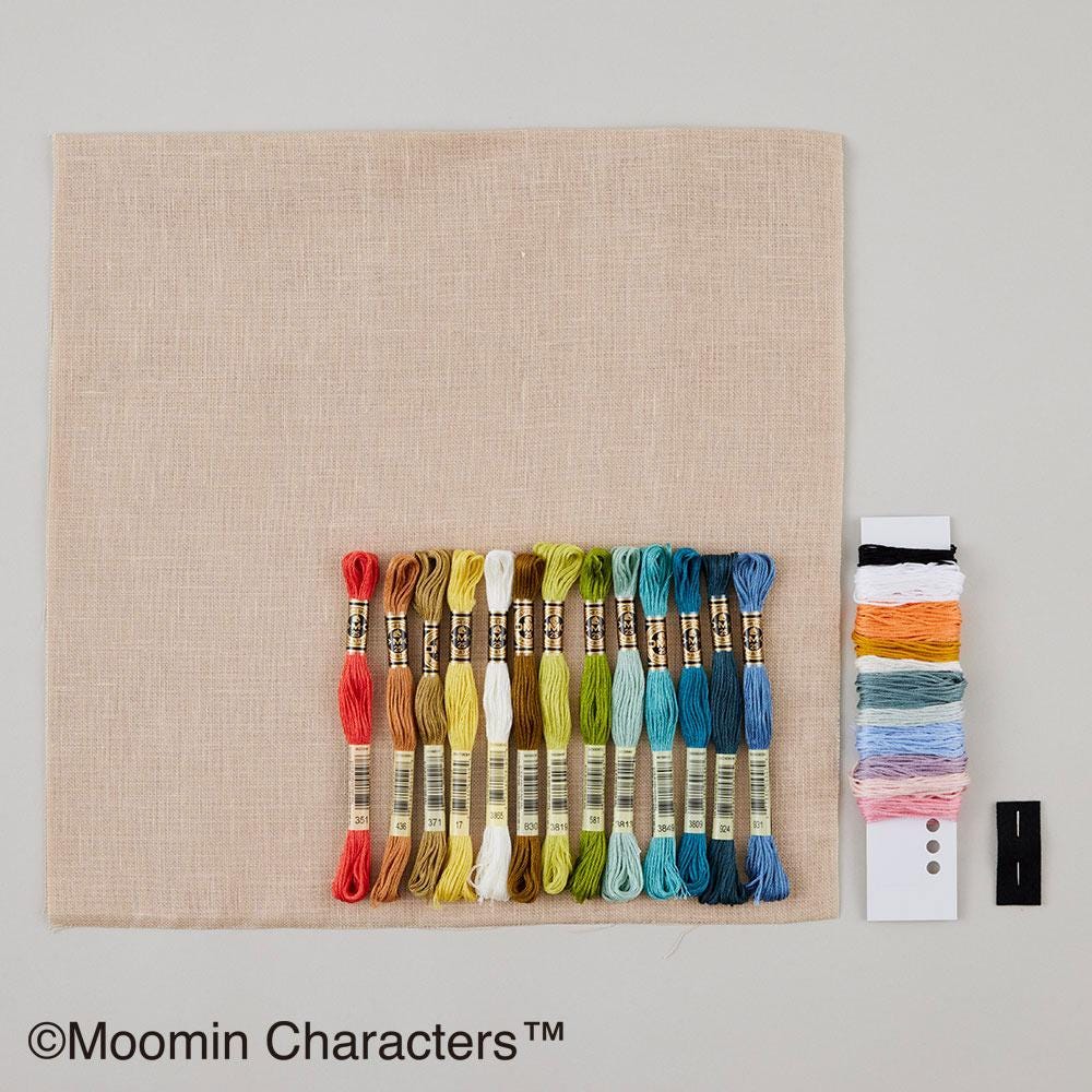 a collection of embroidery floss and a spool of thread, arranged on a beige background.