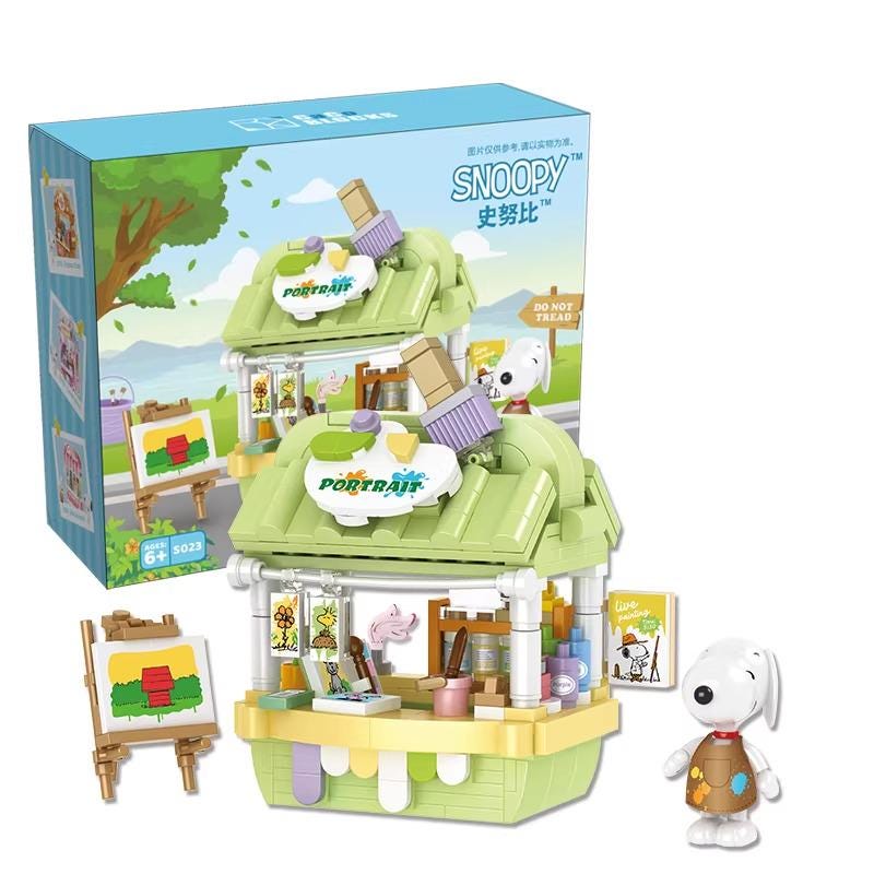 a toy set of a cartoon character, specifically a Snoopy character, with a painting easel and various art supplies. The toy set is displayed in front of its packaging, which is a box with a cartoon image of Snoopy.