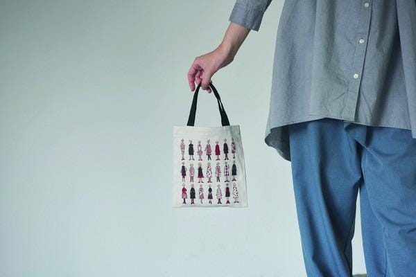 A person is holding a small bag with a printed design of various human figures.