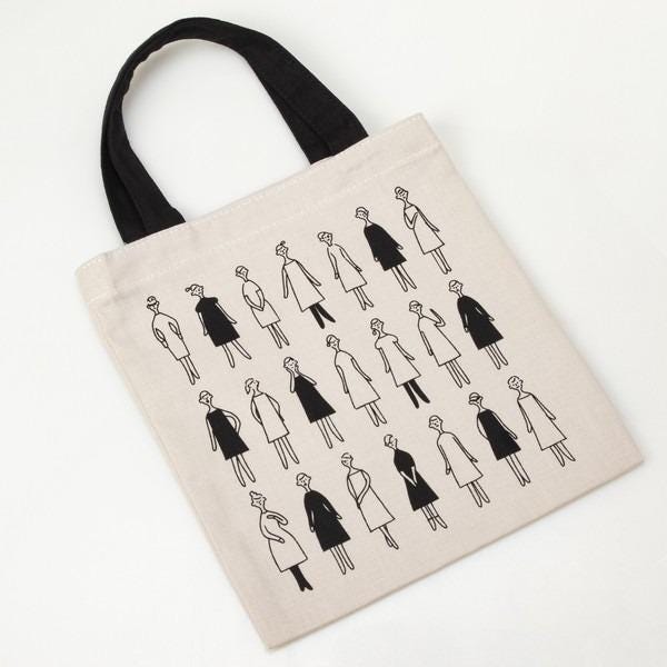 a beige tote bag with a black and white pattern of stylized human figures.