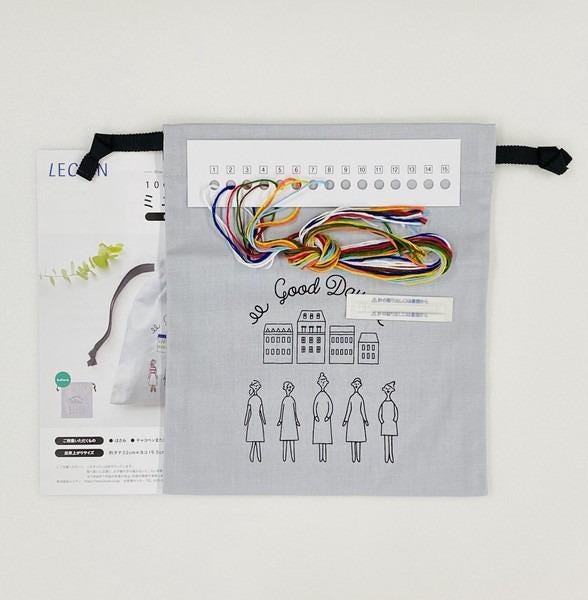 a gray bag with a printed design and text, along with a spool of thread and a booklet or pattern.