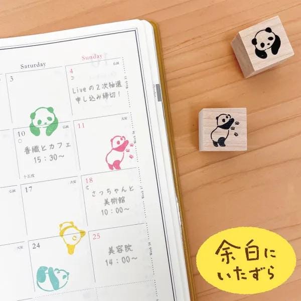 a calendar with a panda-themed design, a set of colorful rubber stamps, and a yellow sticker with Japanese text.