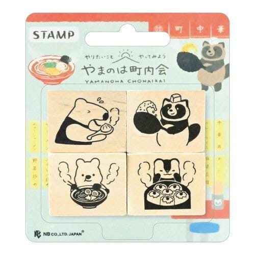 The image is a stamp package containing four wooden stamps depicting various cartoon animal characters, including a bear, a cat, and a panda, along with illustrations of food items such as a bowl of noodles and a plate of sushi.