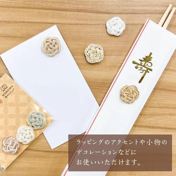 various decorative items, including a white envelope with a red stripe, a pair of chopsticks, and several small knitted or woven objects. There is also a text box with Japanese characters in the image.