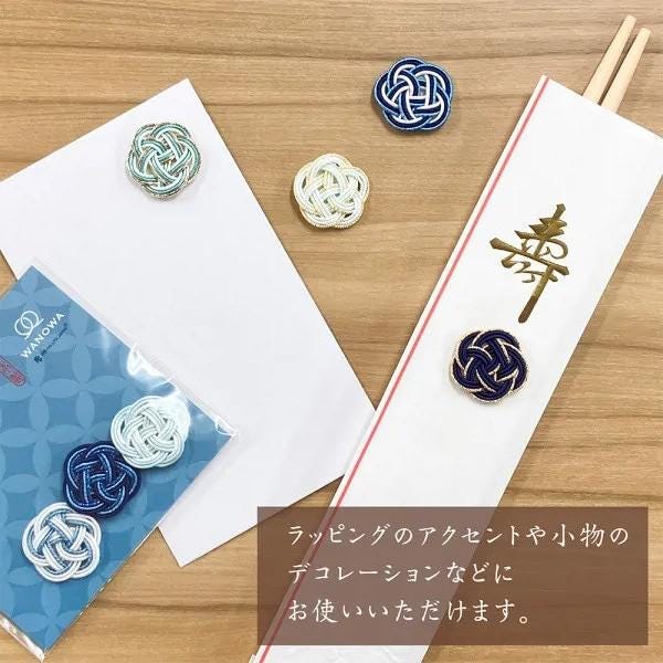 a variety of decorative items, including a white envelope, chopsticks, and several small knitted or woven objects, all placed on a wooden surface.
