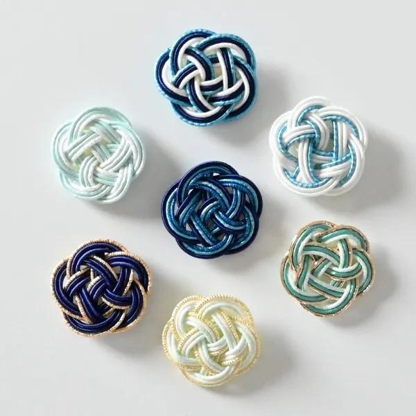 a collection of seven intricately woven objects, each with a unique knot pattern and color scheme.