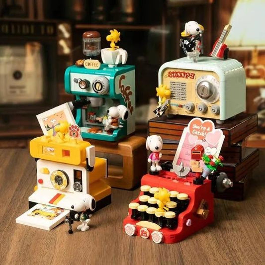 a collection of various Peanuts-themed toys and memorabilia, including a coffee machine, typewriter, radio, and other Peanuts-inspired items.