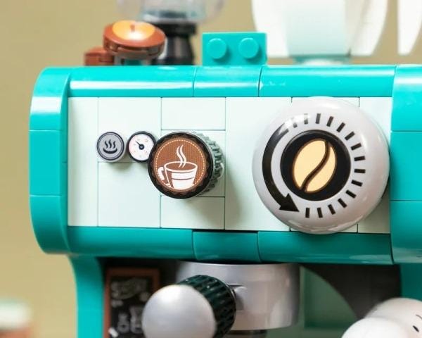 A close-up view of a turquoise and white coffee machine with various buttons and dials, including a coffee cup icon.