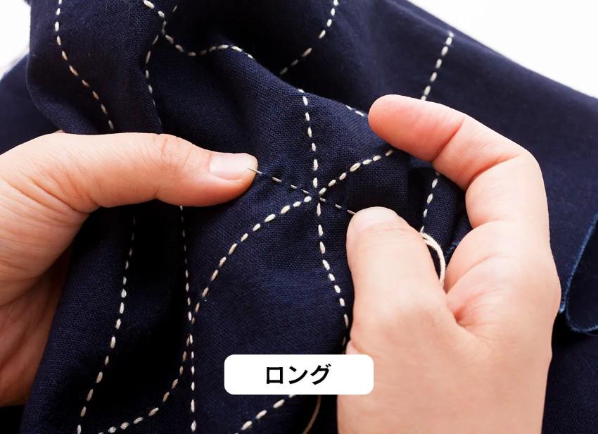 A close-up image of a person's hands holding a piece of fabric with white stitching, possibly engaged in sewing or crafting.