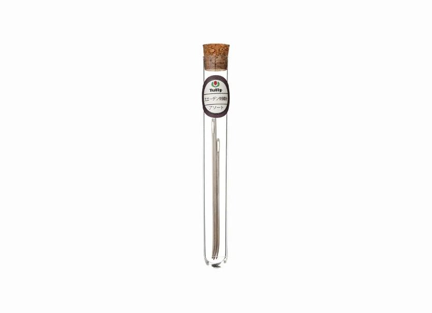 A clear glass tube with a cork stopper, containing a small object, possibly a piece of jewelry or a decorative item.