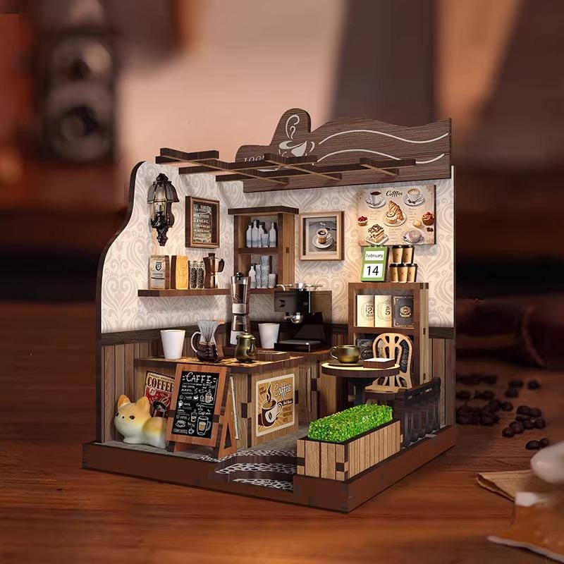 A small, intricately designed miniature coffee shop, complete with a counter, seating area, and various coffee-related items such as cups, saucers, and a coffee machine.
