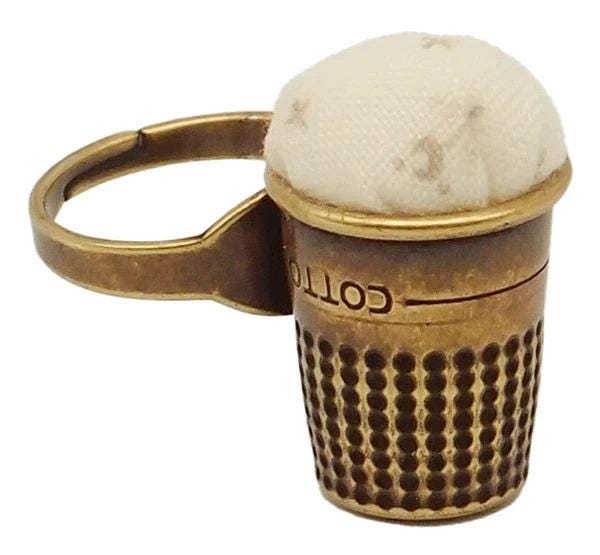 A brass thimble with a white cloth inside, designed for sewing purposes.