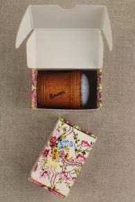 a wooden box with a floral pattern, and a white object inside the box, which appears to be a small wooden item.