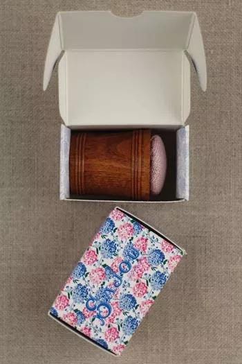 a wooden box with a pink object inside, and a box with a floral pattern on the ground.
