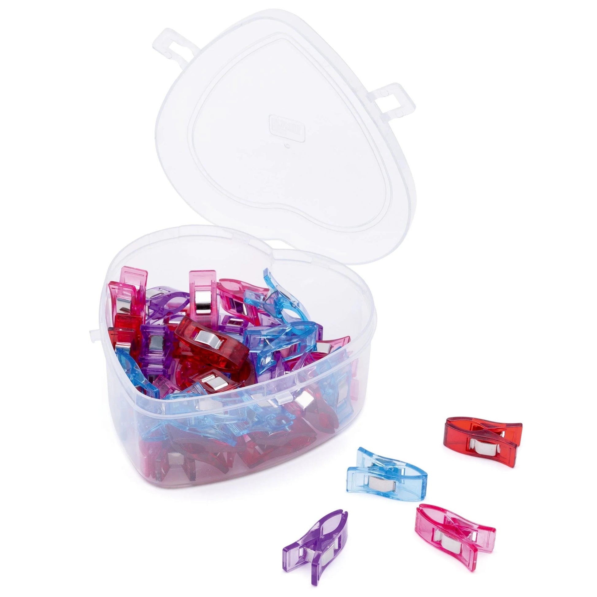 A heart-shaped plastic container filled with colorful plastic clips and a few scattered clips on the floor.