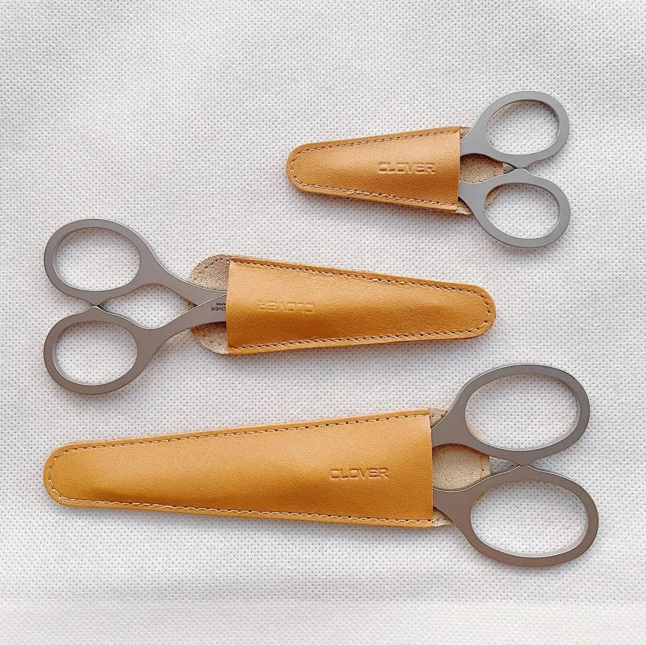 Three pairs of scissors with leather cases, each with the word "CLOVER" printed on them.