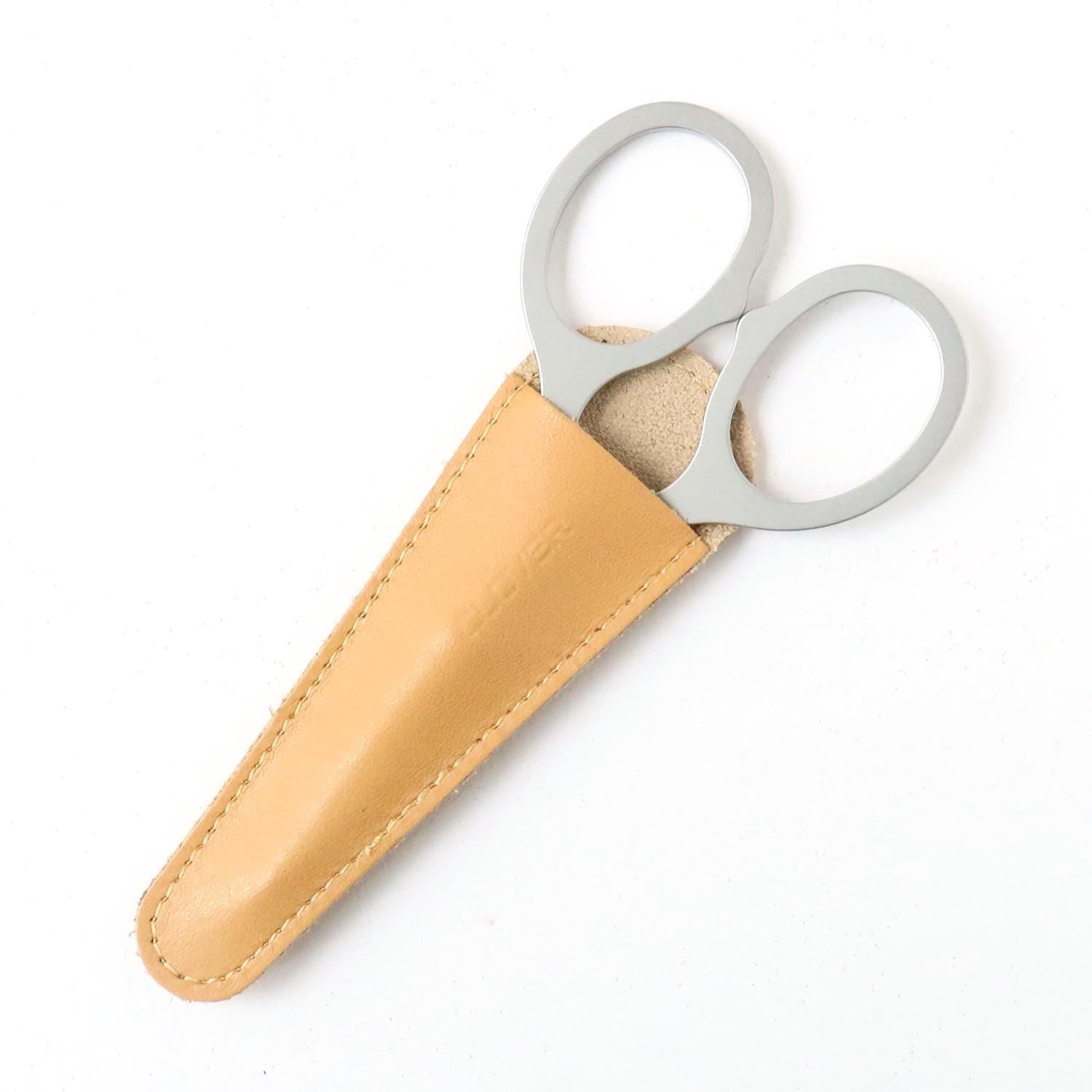 A pair of silver scissors with a tan leather case.