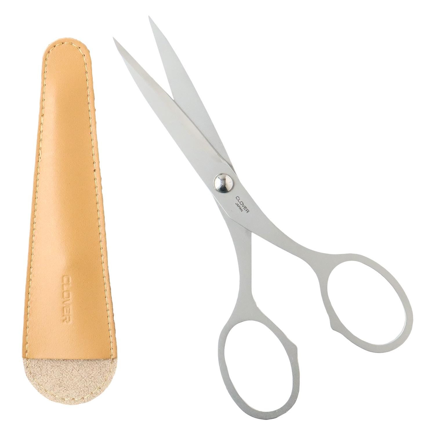 a pair of silver scissors and a leather case with a beige leather strap.