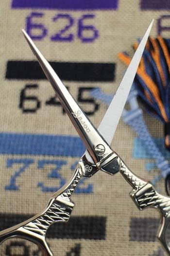 A pair of silver scissors with the brand name "Sterling" on the blades is prominently displayed against a background with numbers and text.