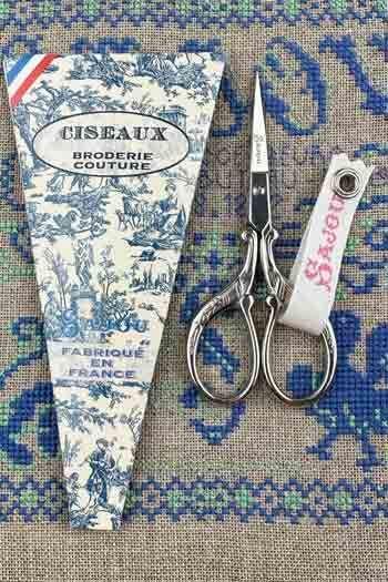 a pair of scissors and a package of fabric scissors, both placed on a patterned fabric background.