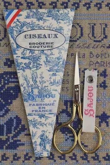 a pair of scissors and a package of fabric with a patterned design, all placed on a patterned background.