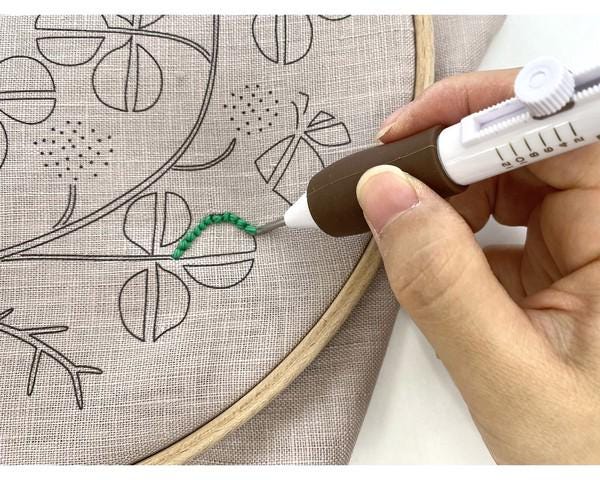 A hand is using a sewing machine to embroider a design onto a fabric.
