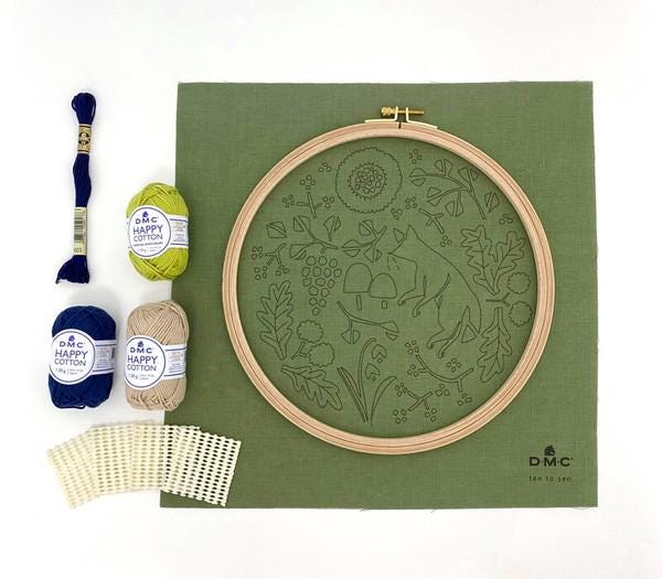 a sewing kit containing various embroidery supplies, including yarn, a hoop, and a needle, arranged on a green background.