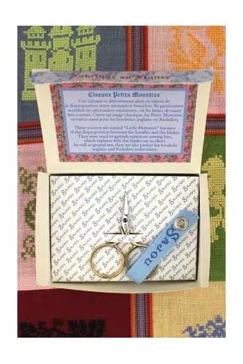 a pair of scissors with a blue tag attached to it, placed inside a box with a label.