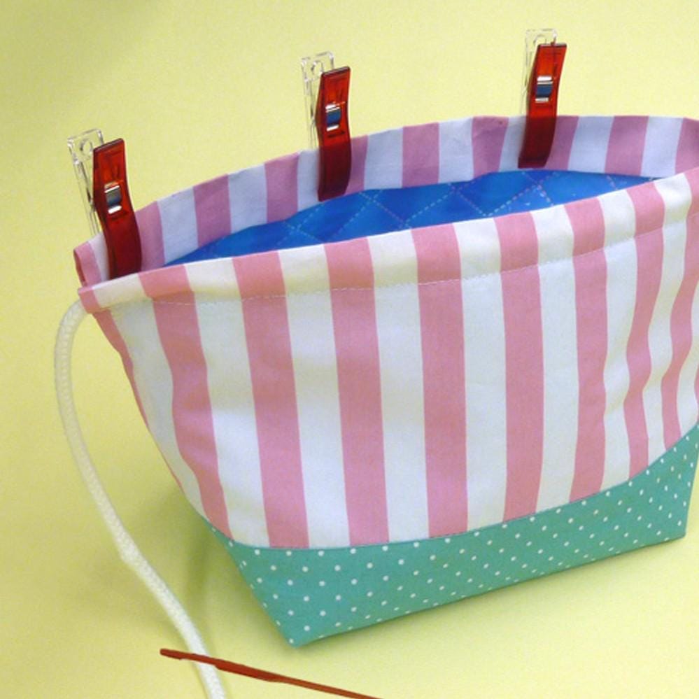 A colorful striped bag with polka dots and red clothespins attached to the top corners.