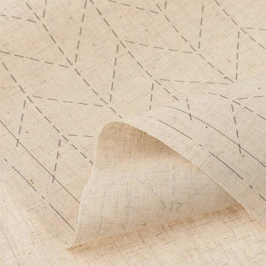 a close-up view of a beige fabric with a geometric pattern, featuring a repeating diagonal line design.