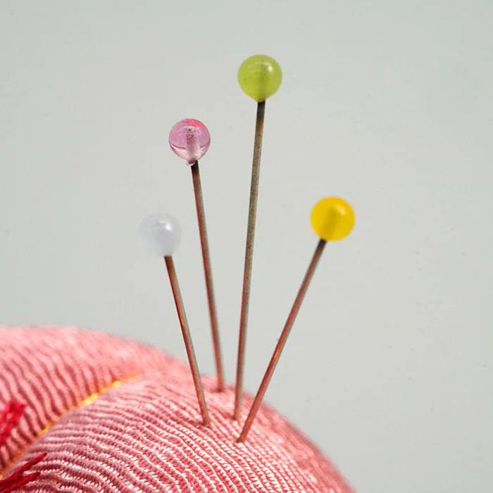 four colorful pins, each with a unique color: pink, green, yellow, and white.