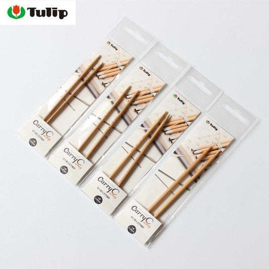 a collection of wooden knitting needles packaged in clear plastic, arranged in a row on a white background.