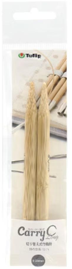 A package containing two bamboo knitting needles, with a blurred background that includes other knitting needles and a notebook.