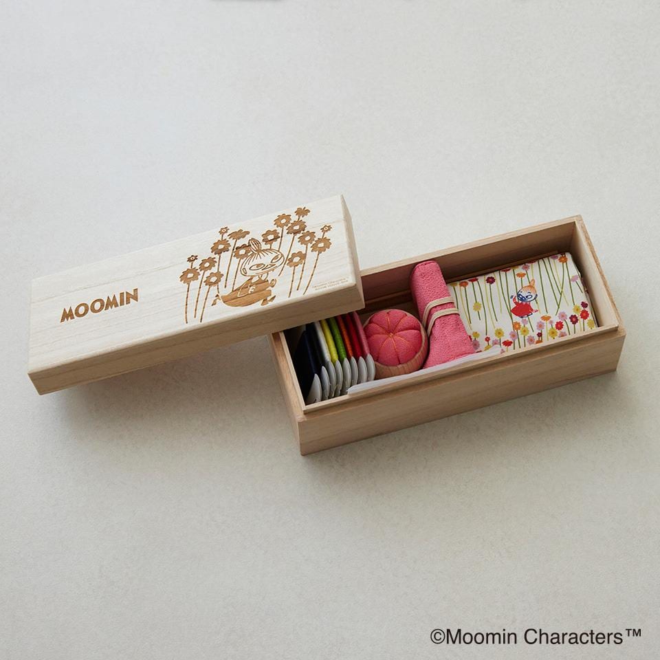 A wooden box with a lid, containing various items such as a pink ball, a small toy, and some other objects.