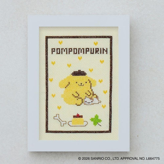 The image is a framed cross-stitch depicting a yellow dog with a bone, surrounded by hearts and other small objects.