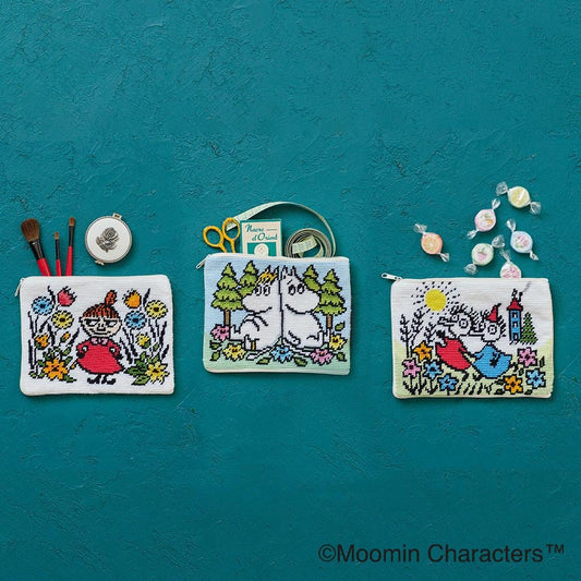 three colorful purses or pouches with illustrations of Moomin characters, including Minnie Mouse, Olaf, and other popular characters from the Moomin series. The purses are arranged on a teal background, and there are also some candy wrappers and a small container of scissors visible in the image.