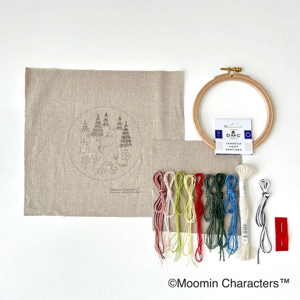 various embroidery supplies, including a hoop, thread, needles, and a piece of fabric with a design on it.