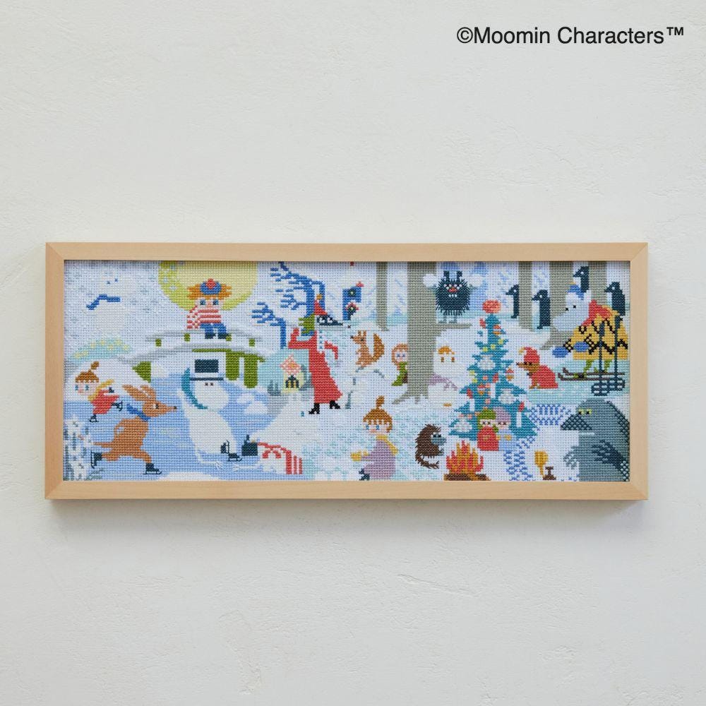 The image is a framed cross-stitch embroidery depicting various characters and scenes, including a snowman, a Christmas tree, and other festive elements.