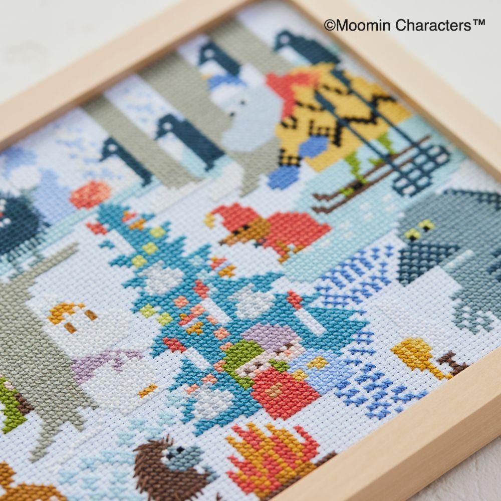 The image is a cross-stitch embroidery featuring various colorful characters and scenes, including animals, people, and landscapes.