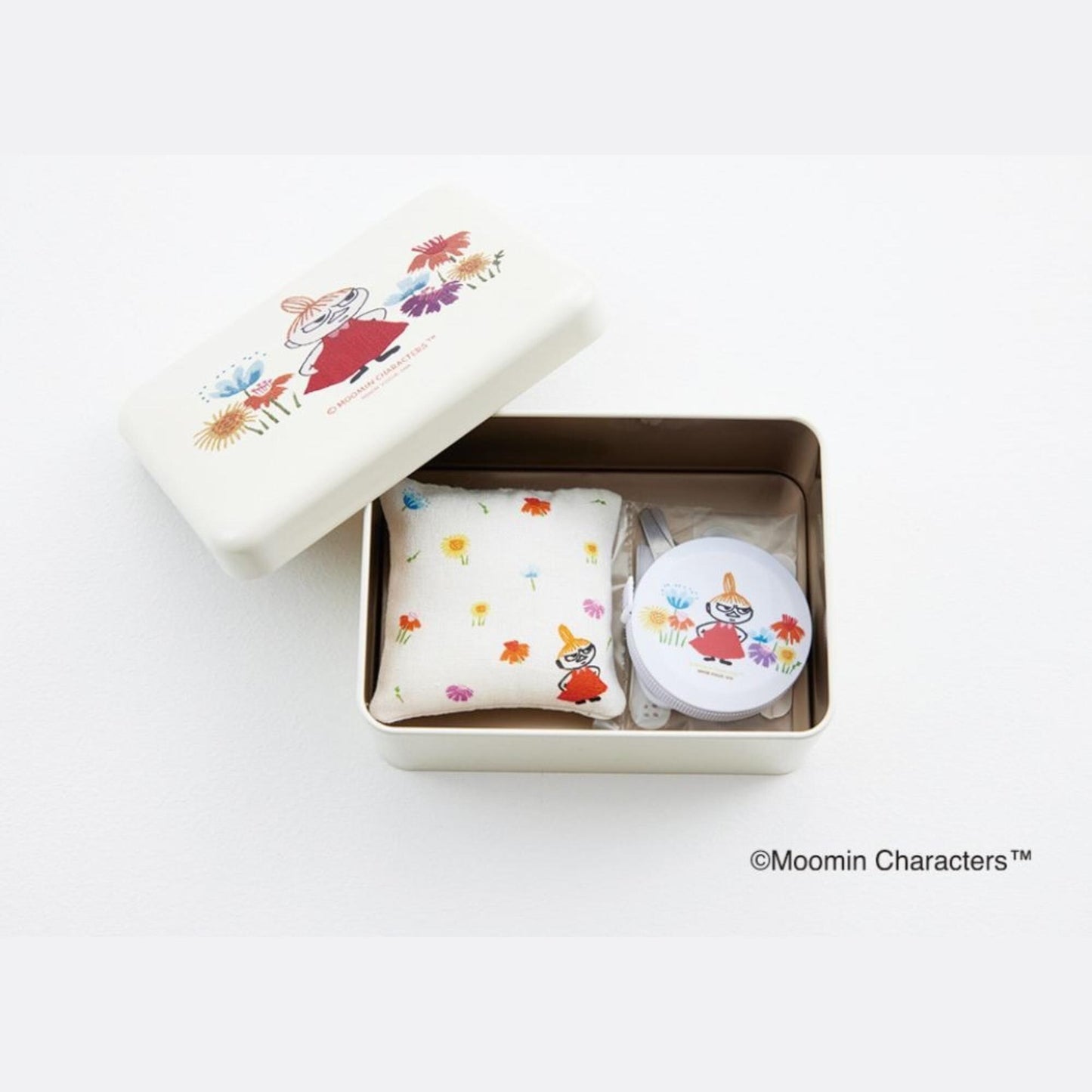 A white box containing a small white pillow with colorful flowers and a round white object with a similar design.