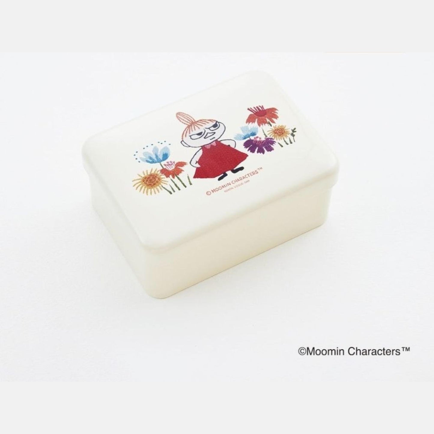A white rectangular container with a colorful illustration of a character surrounded by flowers on its lid.