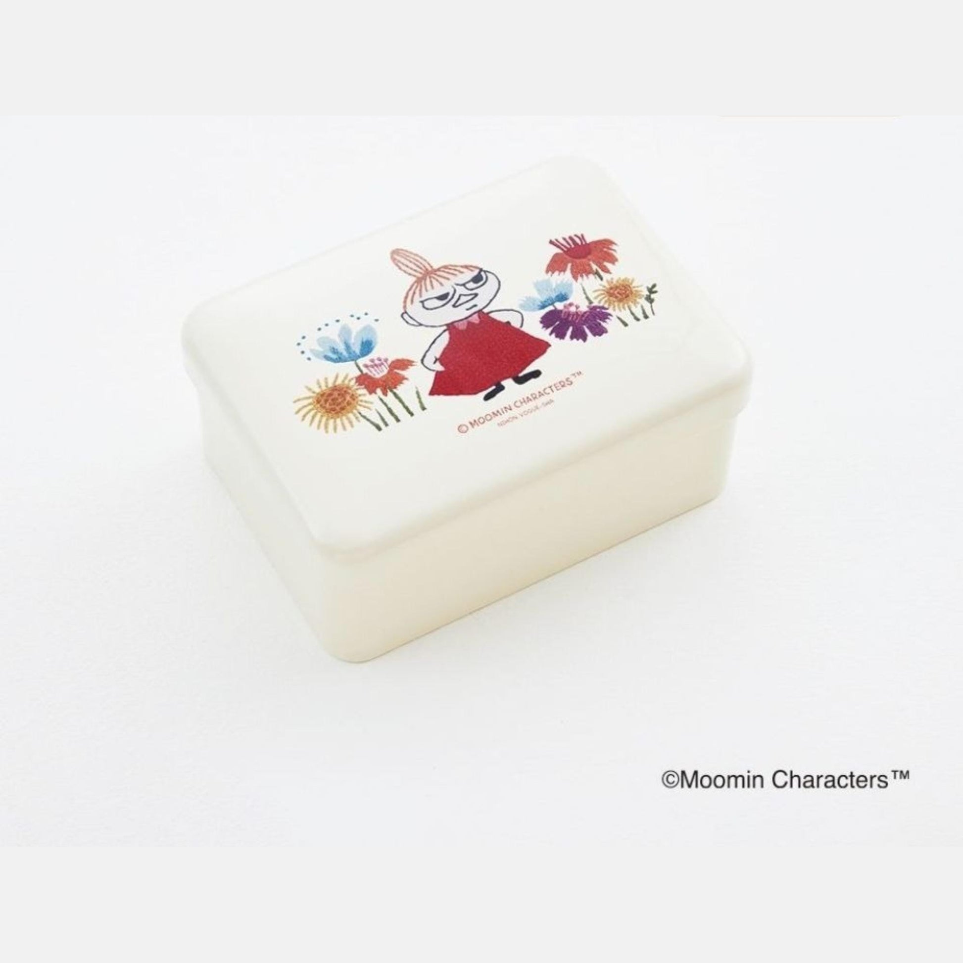 A white rectangular container with a colorful illustration of a character surrounded by flowers on its lid.