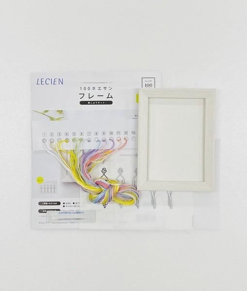 a white frame and a package of embroidery floss, with the package displaying instructions and illustrations for using the product.